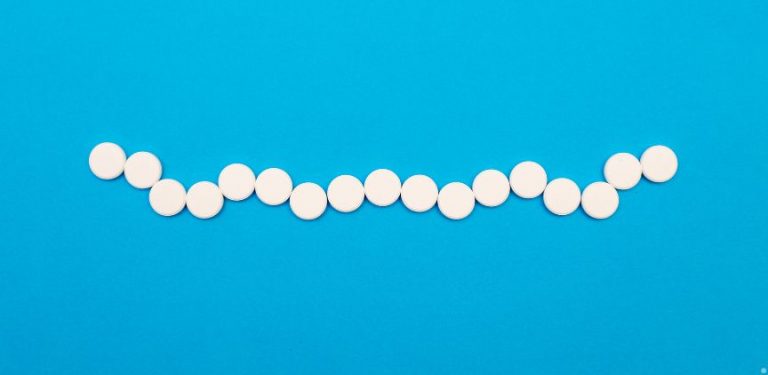 Round white pills in a line on a blue background.