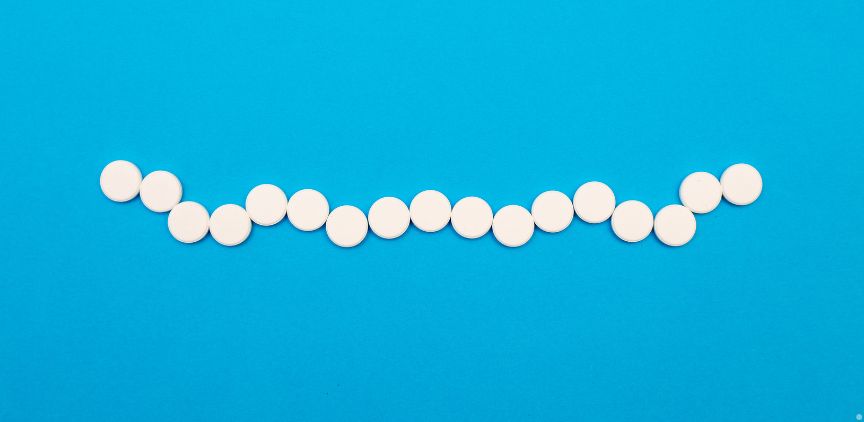 Round white pills in a line on a blue background.