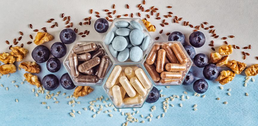 Different supplements for brain health in small containers, surrounded by blueberries and granola.