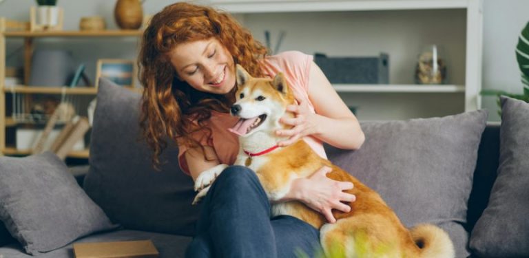 A woman hugging her dog while sitting on a couch.